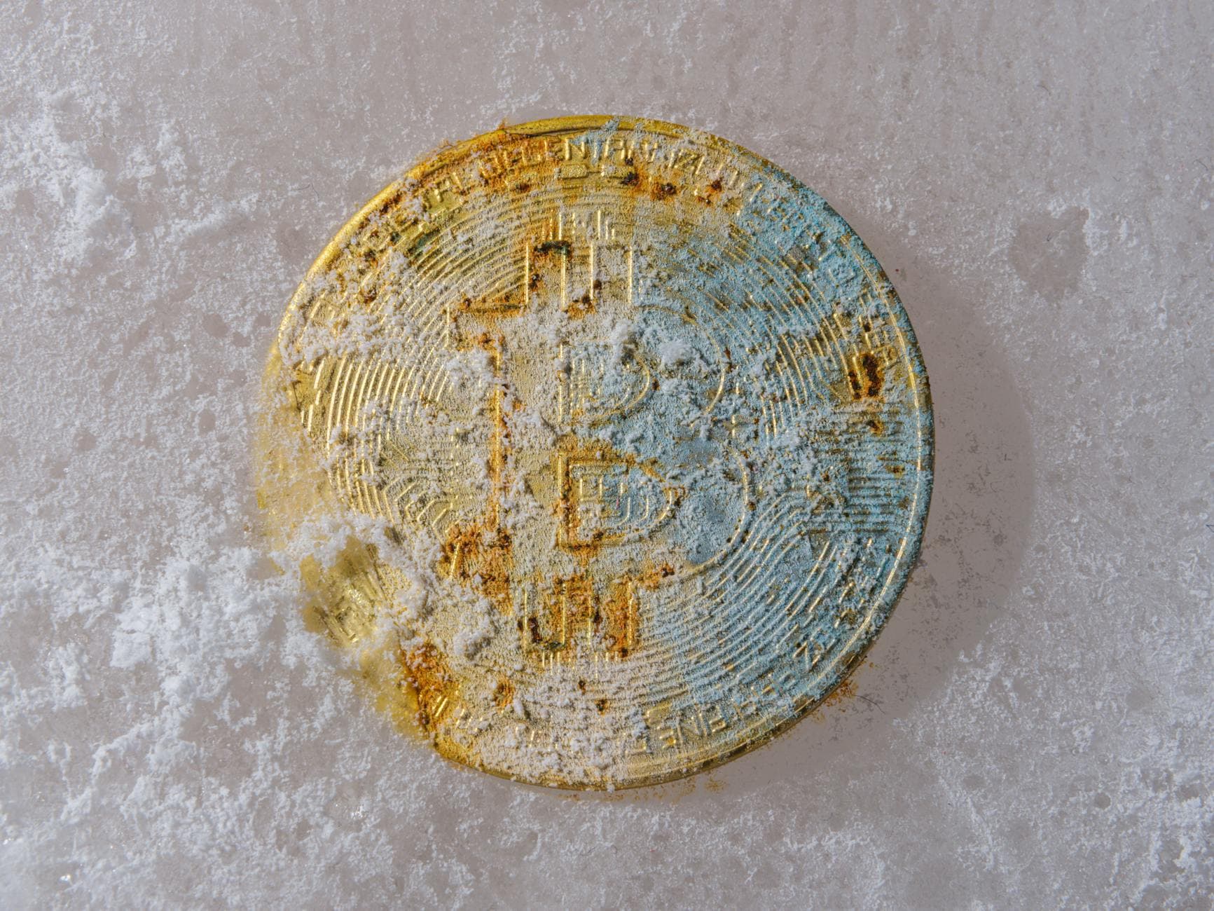 A gold Bitcoin coin partially covered in ice, symbolizing cryptocurrency's unpredictable market conditions.