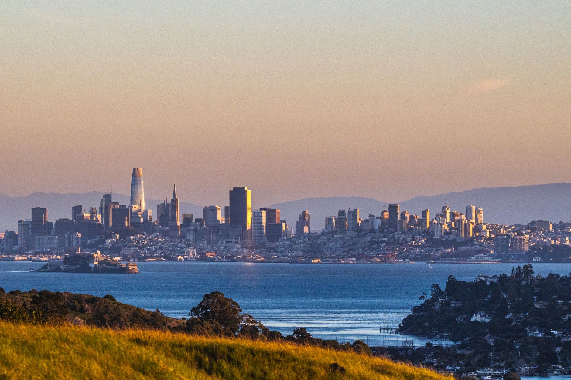 Scenic view of San Francisco skyline and bay during sunset with iconic landmarks.